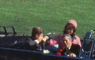President Kennedy is hit by sharpshooters as his wife looks on. 